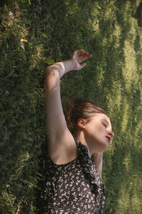 Side view of young woman with eyes closed against plants