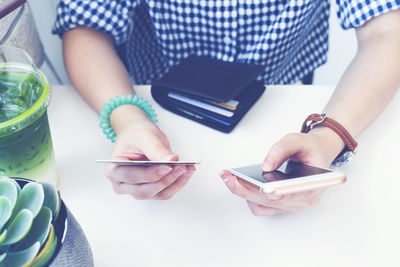 Midsection of man using mobile phone on table