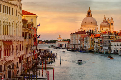 Santa maria della salute by grand canal and building against cloudy sky during sunset