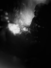 Close-up of young woman holding cigarette at night