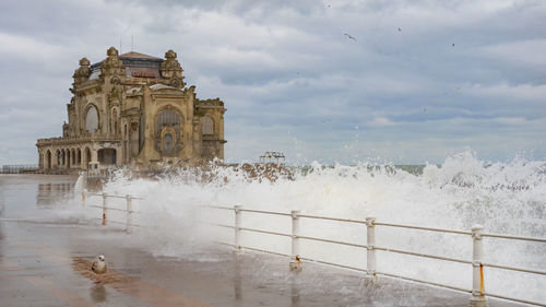 Building by sea against cloudy sky