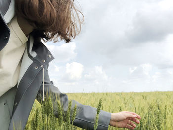 Rear view of man standing on field against sky