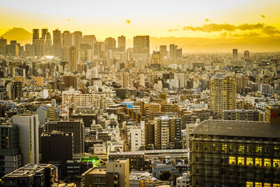 Aerial view of modern buildings in city against sky during sunset