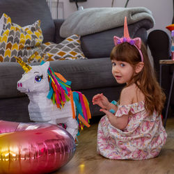 Cute girl sitting on the floor with a balloon and a pinata