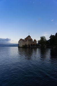 Building by lake against sky