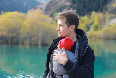 Portrait of man holding red while standing by lake