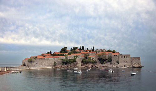 Buildings by sea against sky