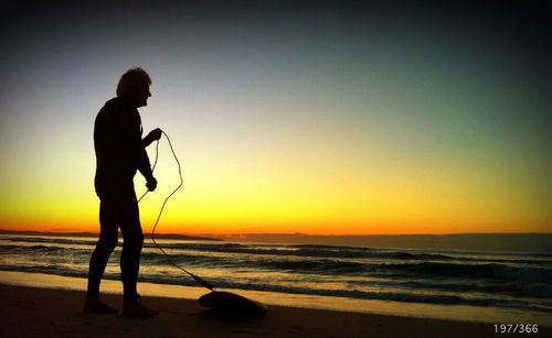 Silhouette of people standing on beach at sunset