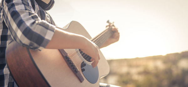 Midsection of boy playing guitar outdoors