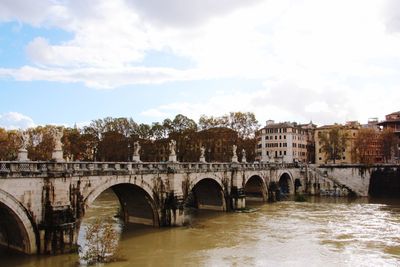 Bridge over river in city against sky