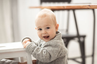 Baby boy himself is standing by the chair, the concept is the first steps and safety. 