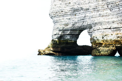 Rock formation in sea against sky