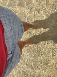 Low section of person standing on sand at beach