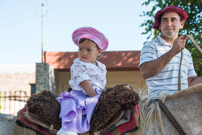 Man standing by girl sitting on horse