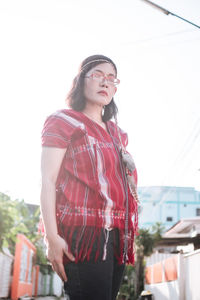 Portrait of young woman standing against clear sky