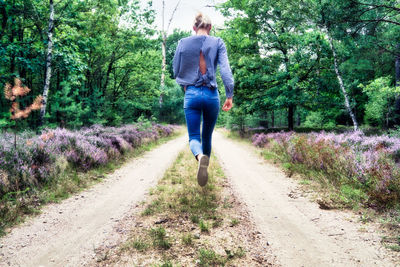 Rear view of woman walking on footpath amidst trees