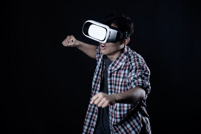 Man holding camera while standing against black background