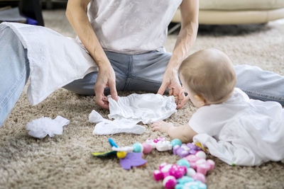 Midsection of woman holding diaper by baby girl at home