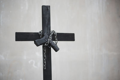 Handgun with chain on cross against wall