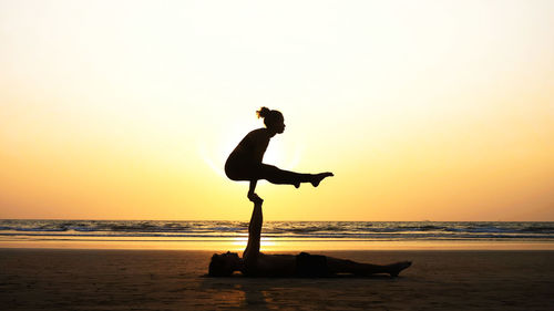 Man and woman doing yoga at beach