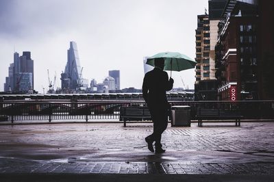 Rear view of man with umbrella walking on rainy day