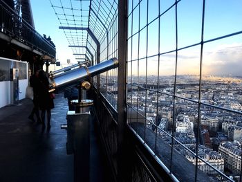 People standing by railing in city against sky