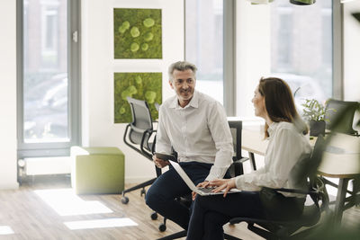 Smiling partner working on laptop while sitting on chair at office