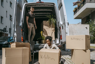 Smiling woman arranging boxes with boyfriend standing in van trunk