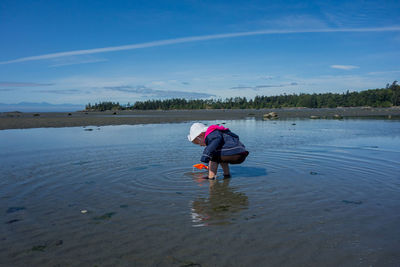 Girl playing in sea against sky