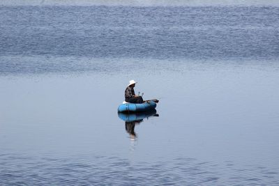 Rear view of man sitting on boat in river