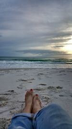 Low section of woman on beach against sky