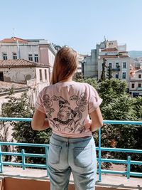 Rear view of woman standing against building in city