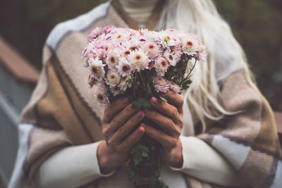 Midsection of senior woman holding flower bouquet