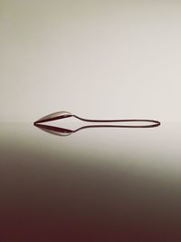 Close-up of spoon on glass table against gray background