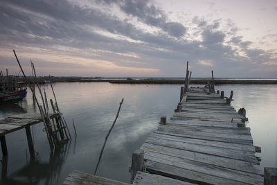 Pier on lake against sky during sunset