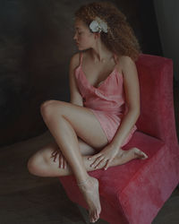 Young woman looking down while sitting on sofa