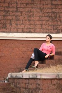 Full length of woman sitting against wall