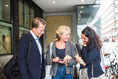 Happy male and female entrepreneurs communicating while standing by office