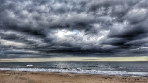 Scenic view of beach against cloudy sky