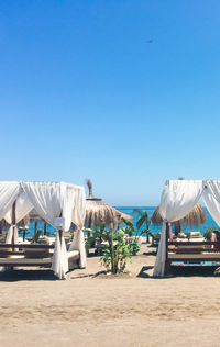 Deck chairs on beach against clear blue sky