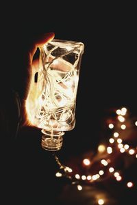 Close-up of illuminated light bulb against black background