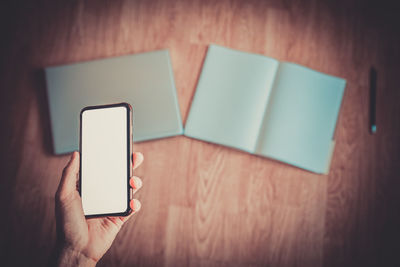 Close-up of person holding smart phone on table