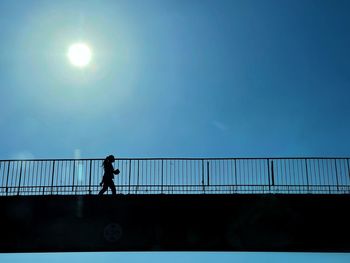 Silhouette man standing on bridge against sky