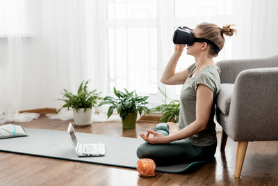 Vr yoga. a young woman sits in a lotus position in a virtual reality headset, doing yoga