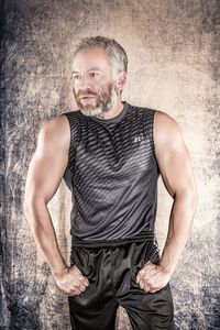Portrait of man standing against gray background