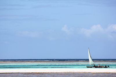 People relaxing at beach against sky