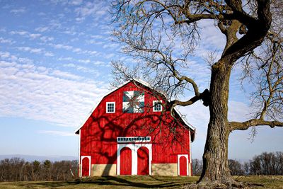 Red house on field against sky