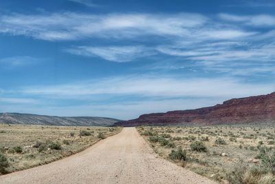 Dirt road amidst landscape against sky