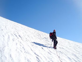 Low angle view of person on snowcapped mountain against clear sky