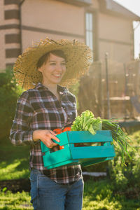 Portrait of young woman wearing hat while standing against trees